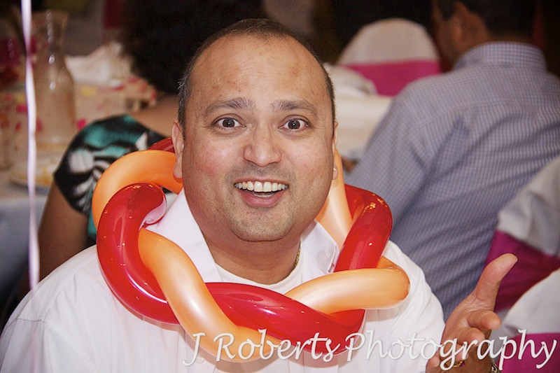 Man with balloon necklace having fun at party - party photography sydney